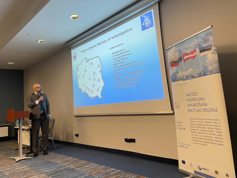 Vīrietis stāsta par ekrānā uz sienas redzamu prezentāciju